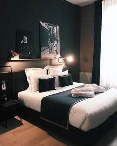 a bed with white and black sheets in a dark colored room next to a window