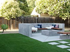 an outdoor living area with grass and concrete blocks in the middle, surrounded by trees