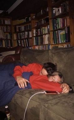 a woman laying on top of a couch next to a book shelf