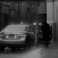 a car is parked in front of a building on a rainy day with the door open