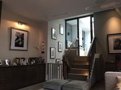 a living room filled with furniture and pictures on the wall next to a stair case