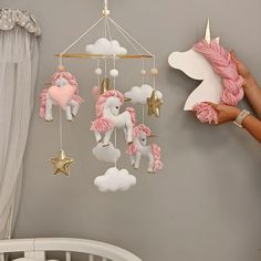 a baby crib mobile with pink and white horses hanging from it's sides