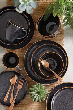 black and gold dinnerware on a table with succulents