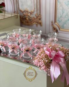 there are many wine glasses with pink bows on the top and flowers in the bottom