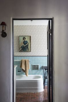 a bathroom with a painting on the wall and a bathtub in the foreground