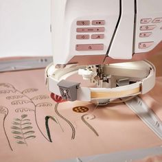 the sewing machine is on top of the pink paper with embroidered letters and numbers that spell it out