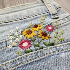 a pair of jeans with embroidered flowers on them