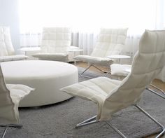 a living room filled with white furniture in front of a large round table and chairs