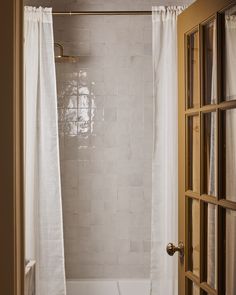 an open door leading to a bathroom with a white tub and shower curtain in it