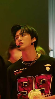 a young man wearing a black shirt and gold necklace