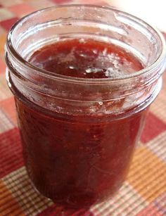 a glass jar filled with jam sitting on top of a checkered tablecloth covered table