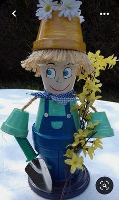 a garden decoration with flowers and a scarecrow figurine sitting on top of a table