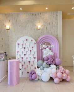 balloons and flowers are arranged on the floor in front of a backdrop for a baby's first birthday party