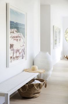 a large white vase sitting on top of a wooden floor next to a shelf filled with hats