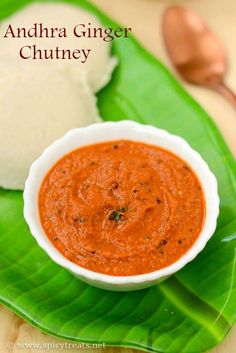 there is a bowl of red sauce on a green plate