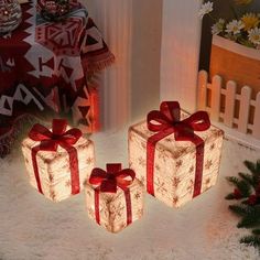 three presents are wrapped in red ribbon and sitting on the floor next to christmas decorations