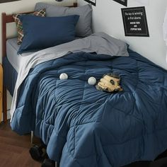 a baseball glove and ball on a blue comforter in a room with wood floors