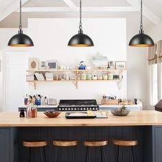 a kitchen island with three hanging lights above it and two stools in front of it