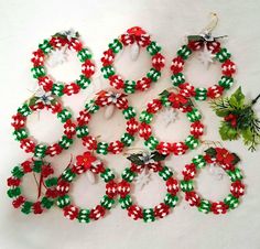 several christmas wreaths are arranged on a white surface with red, green and white ribbons