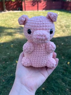 a small pink crocheted teddy bear sitting on top of a green grass covered field