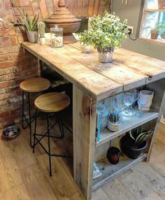 a kitchen island made out of pallet wood with stools and potted plants on top