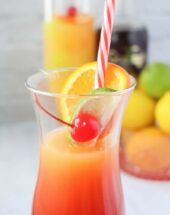 a glass filled with orange juice and topped with a cherry