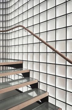 a set of stairs in front of a wall with glass blocks on the walls and wood handrails