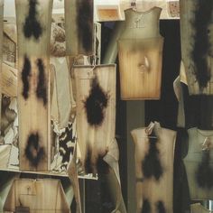 several pieces of clothing with black ink on them and some are hanging from clothes racks