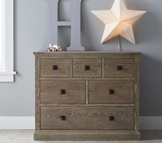 a wooden dresser sitting next to a window with a star on it's top