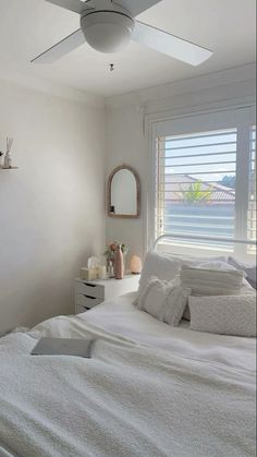 a bedroom with a white bed and ceiling fan