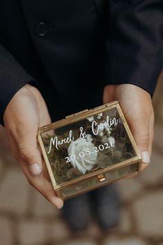 a close up of a person holding a small box with a flower on the inside