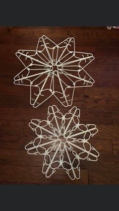 three metal snowflakes sitting on top of a wooden floor