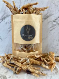 a bag full of dog treats sitting on top of a marble counter next to a pile of sticks