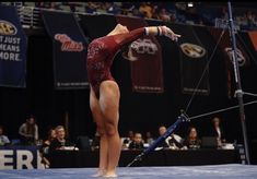 a woman standing on top of a blue floor next to a pole in front of a crowd