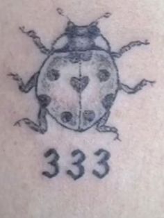 a ladybug tattoo on the back of a woman's shoulder