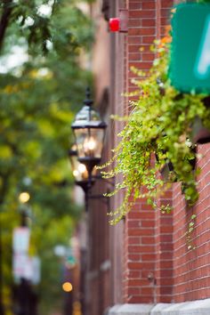 a street sign hanging from the side of a brick building next to a lamp post