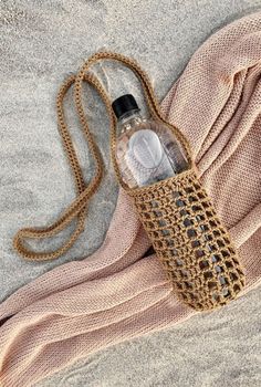 a bottle on the sand with a chain around it and a bag attached to it