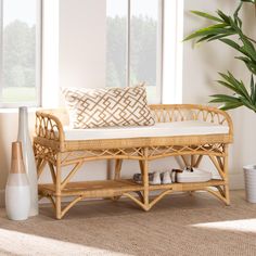 a wicker bench with pillows and vases on the floor next to it in front of large windows