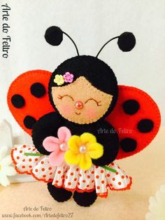 a stuffed ladybug doll is holding a flower