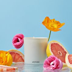 a white candle surrounded by flowers and fruit