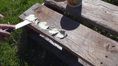 someone using a knife to cut through the bark on a wooden bench in the grass