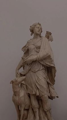 a statue of a woman holding a lamb next to a sheep on a gray background