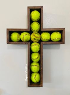 a cross made out of wooden crates filled with green baseballs on top of a white wall