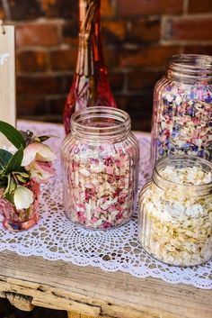 three jars filled with flowers sitting on top of a table