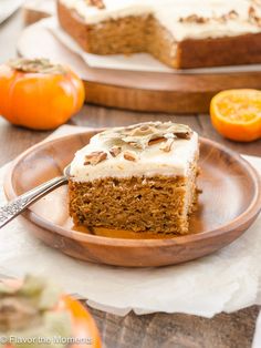 a slice of carrot cake with cream cheese frosting on a plate next to an orange