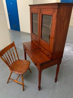 an old wooden desk and chair sitting in a room with blue doors on the wall