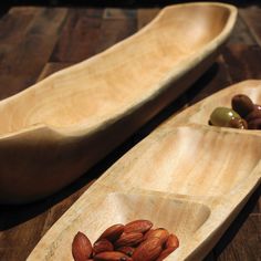 two wooden spoons with almonds and olives in them