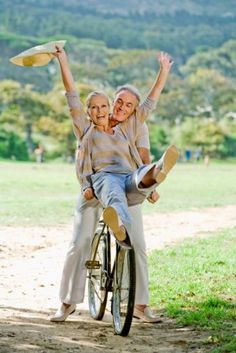 an older couple riding on the back of a bicycle