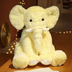 a white stuffed elephant sitting on top of a wooden table