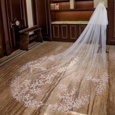 a wedding veil with flowers on it is sitting in front of a mirror and bench